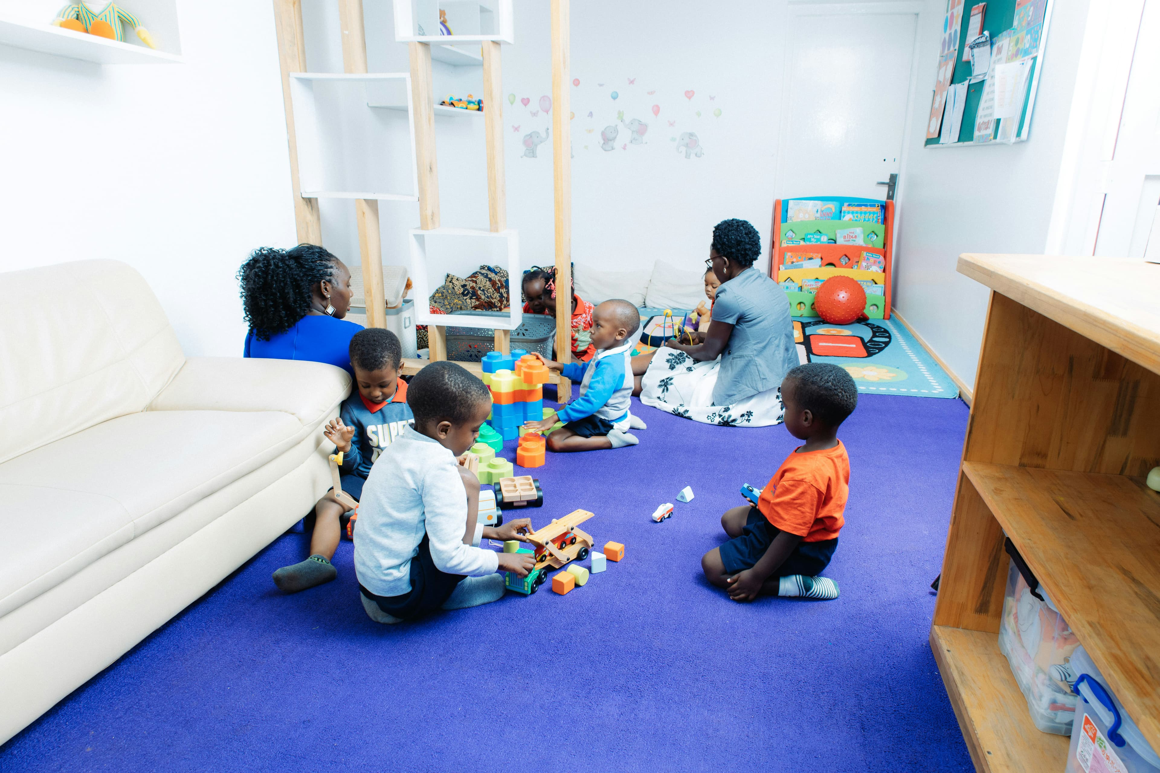 Children playing with building blocks alongside caregivers