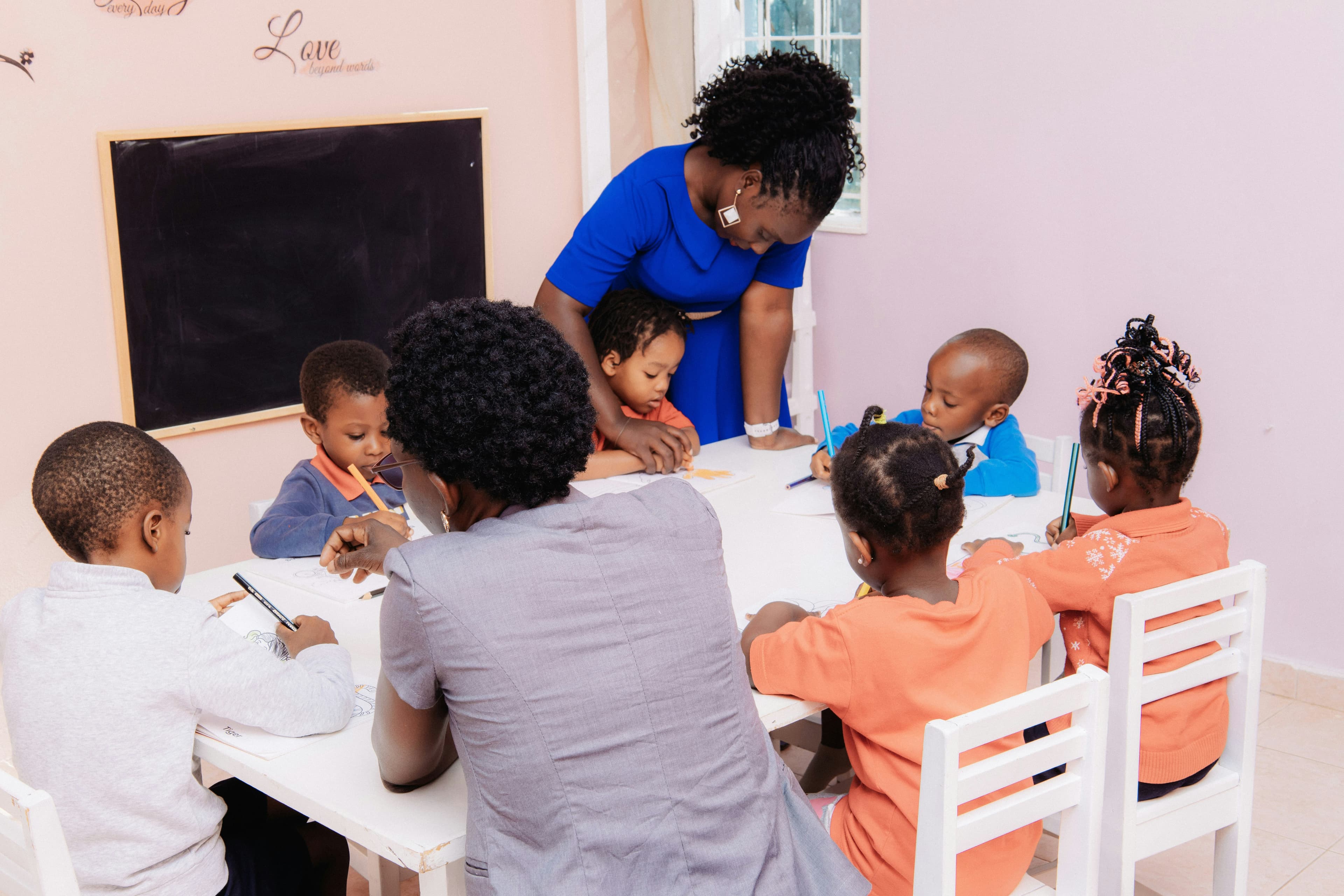 Teacher helping children with writing in a classroom session